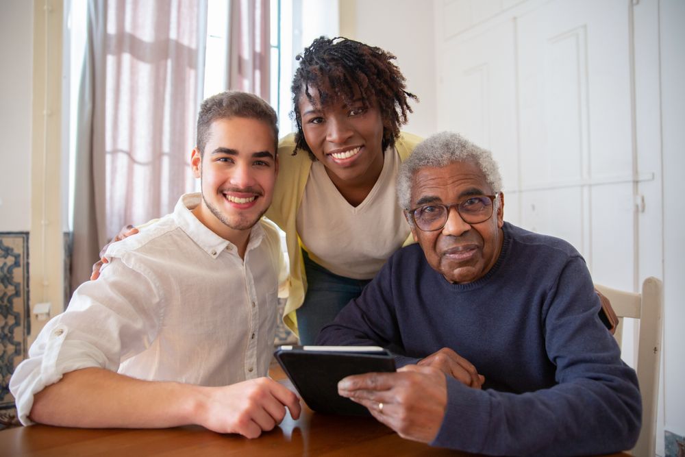 A smiling senior man with his caregiver and family at home