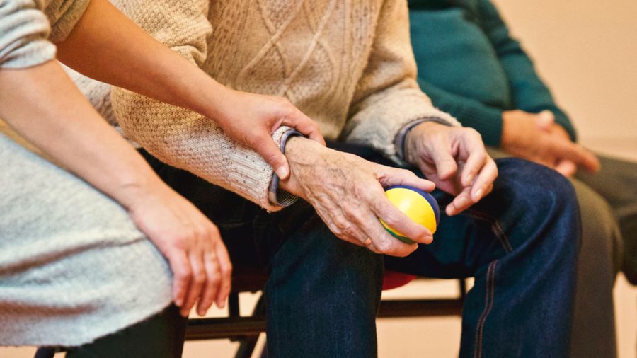 Caregiver gently holding a senior's hands